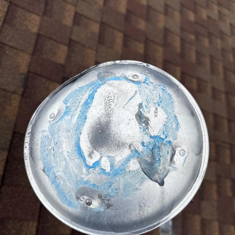 Metal vent cap with hail impact dents on roof shingles