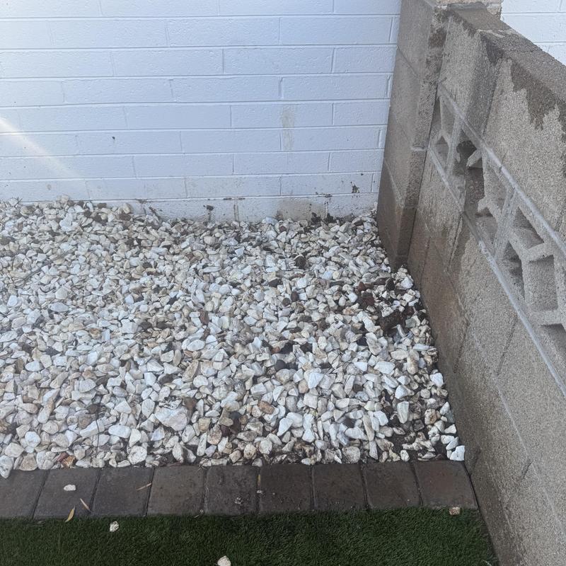 Backyard drainage rock bed beside block wall