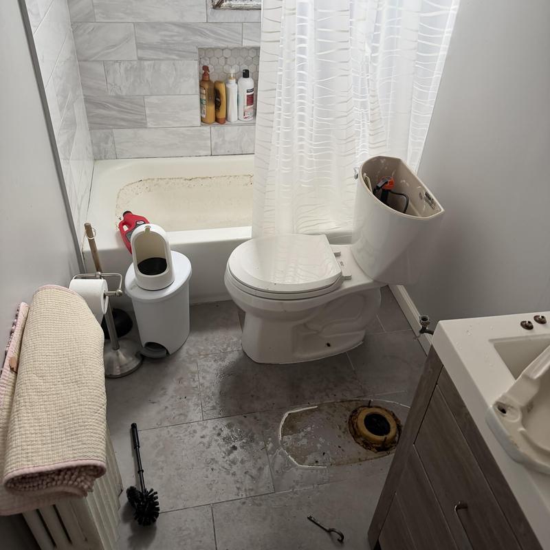 Toilet tank open with flange exposed on bathroom floor