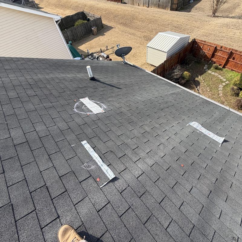 Roof shingles with marked areas for repair on gray roof
