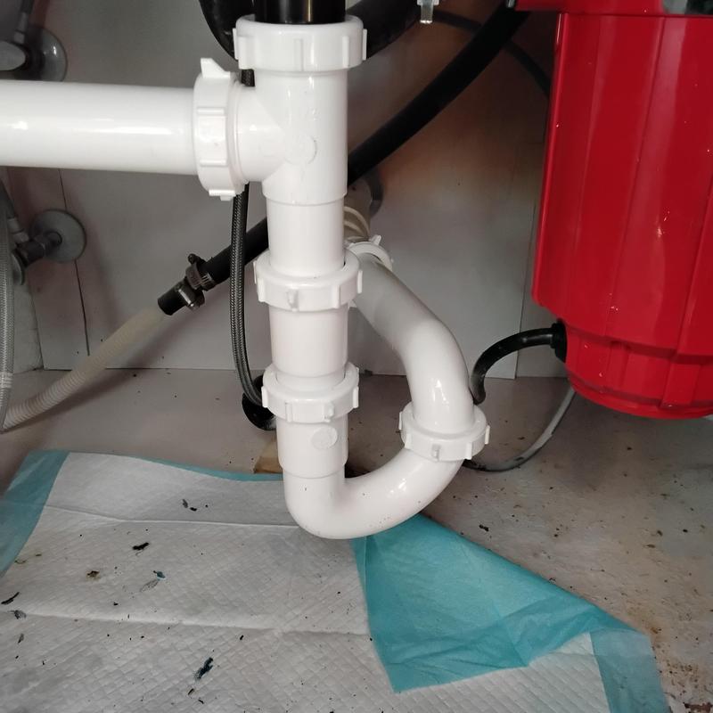 Tubular drain plumbing under kitchen sink with red disposal Tubular drain plumbing under kitchen sink with red disposal