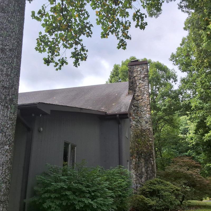 Asphalt shingle roof with stone chimney exterior view