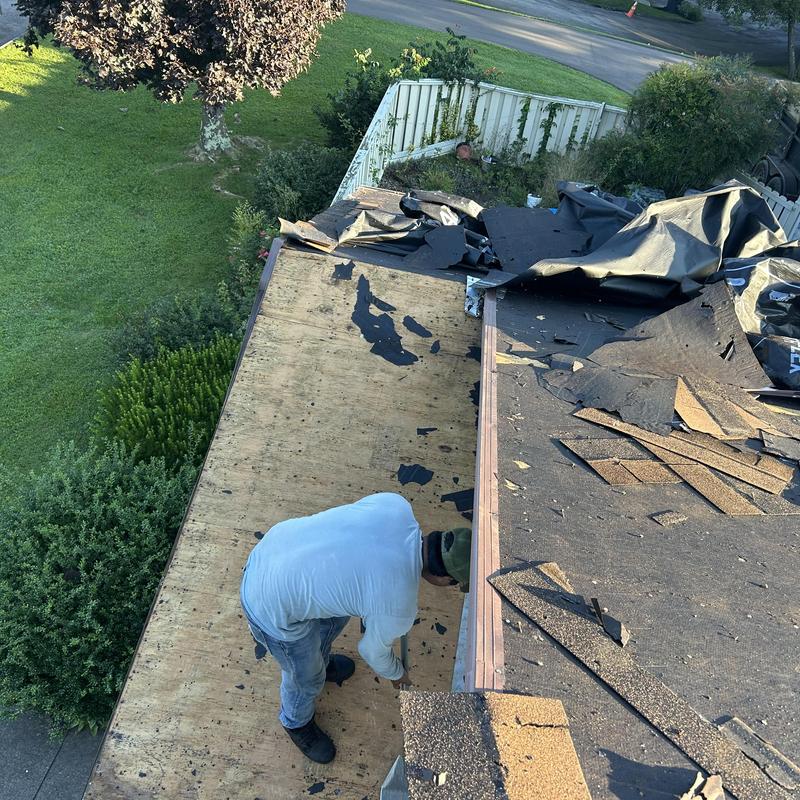 Roof decking removal with shingle debris and worker