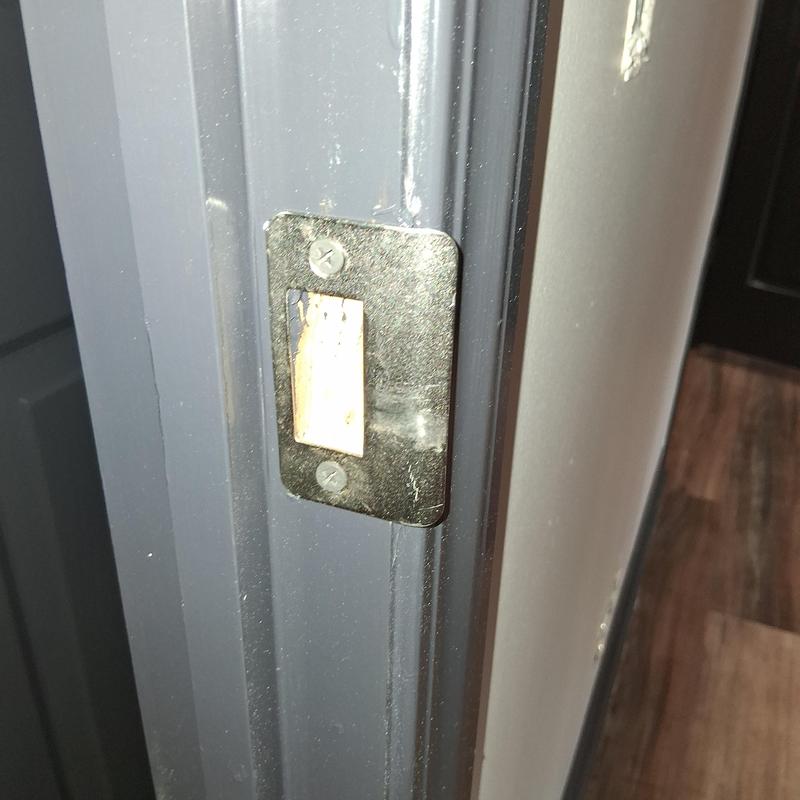 Door latch plate on gray door frame during remodel Door latch plate on gray door frame during remodel