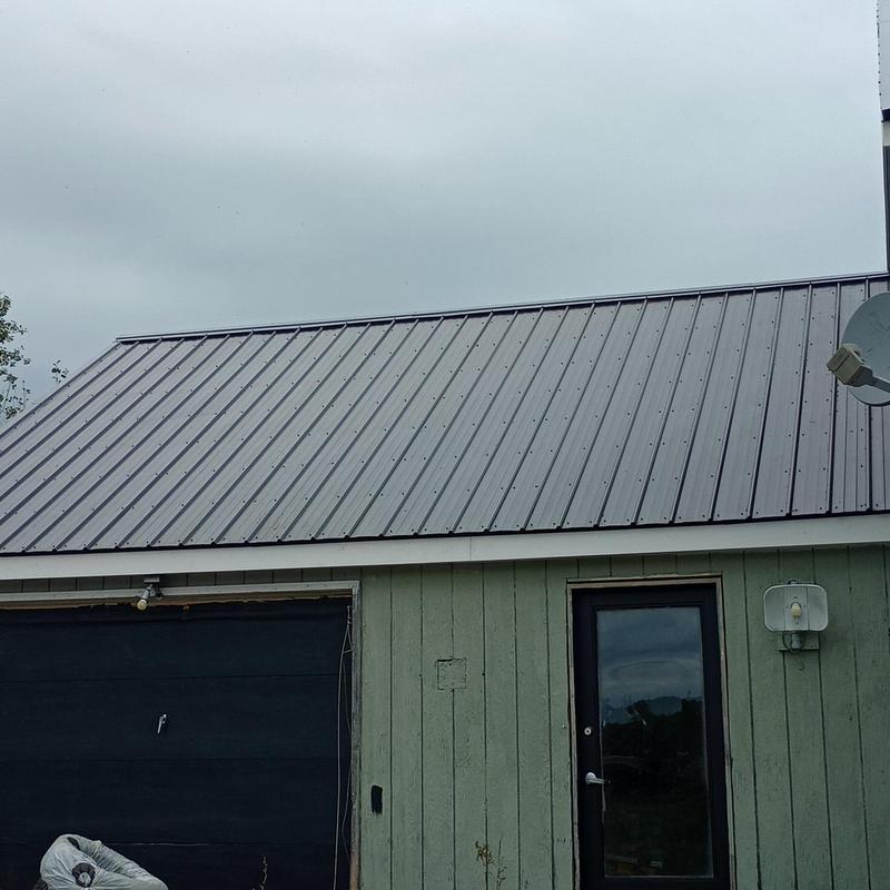 Metal roofing installation on green garage building