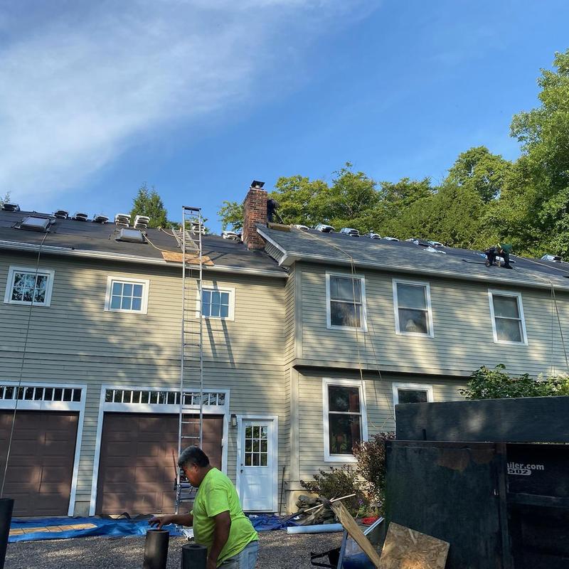 Shingle roof installation with workers on ladder and roof