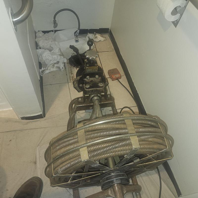 Sewer line drain snake with cable reel in bathroom