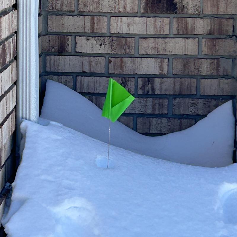Sewer line outdoor cleanout marked with green flag in snow