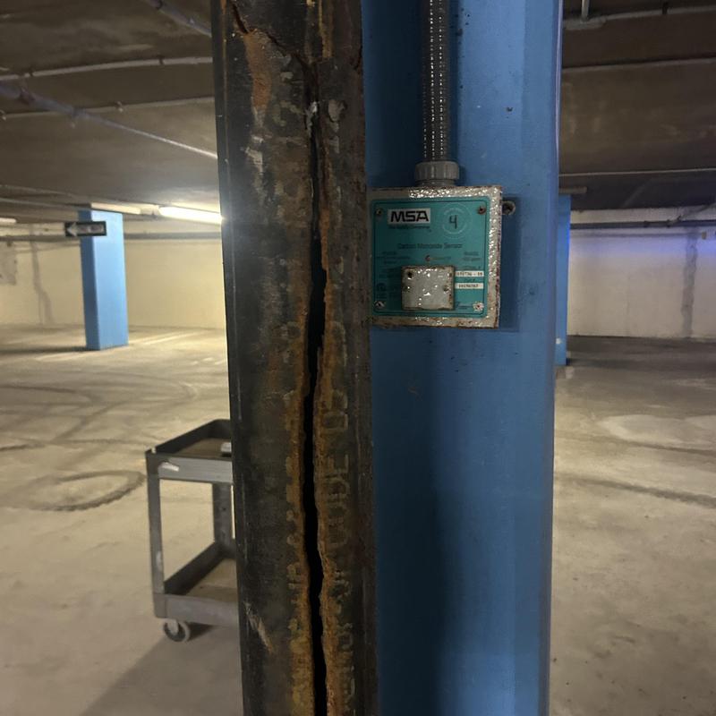 Gas detector sensor mounted on blue column in parking garage