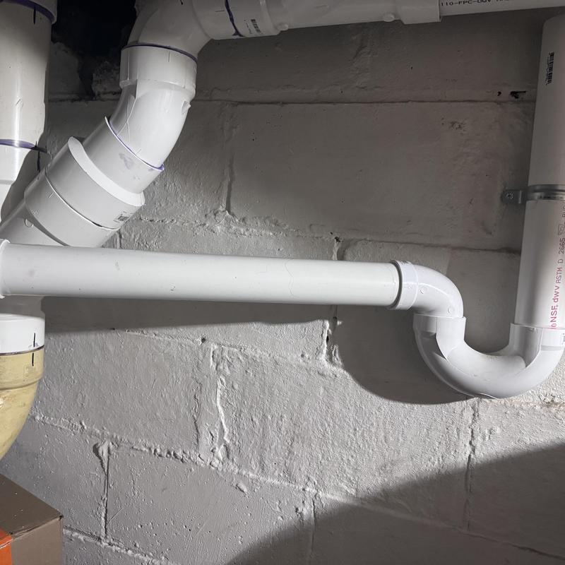 PVC drain pipe with elbow joints in basement wall