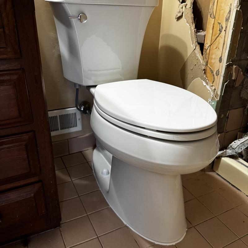 Toilet installation in bathroom with damaged wall