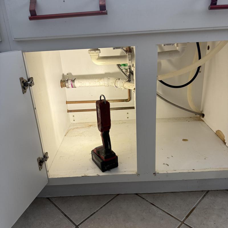 Sink drain pipes with cordless work light inside cabinet