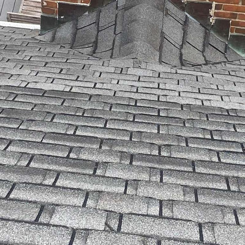 Asphalt shingle roof with visible hail damage near chimney