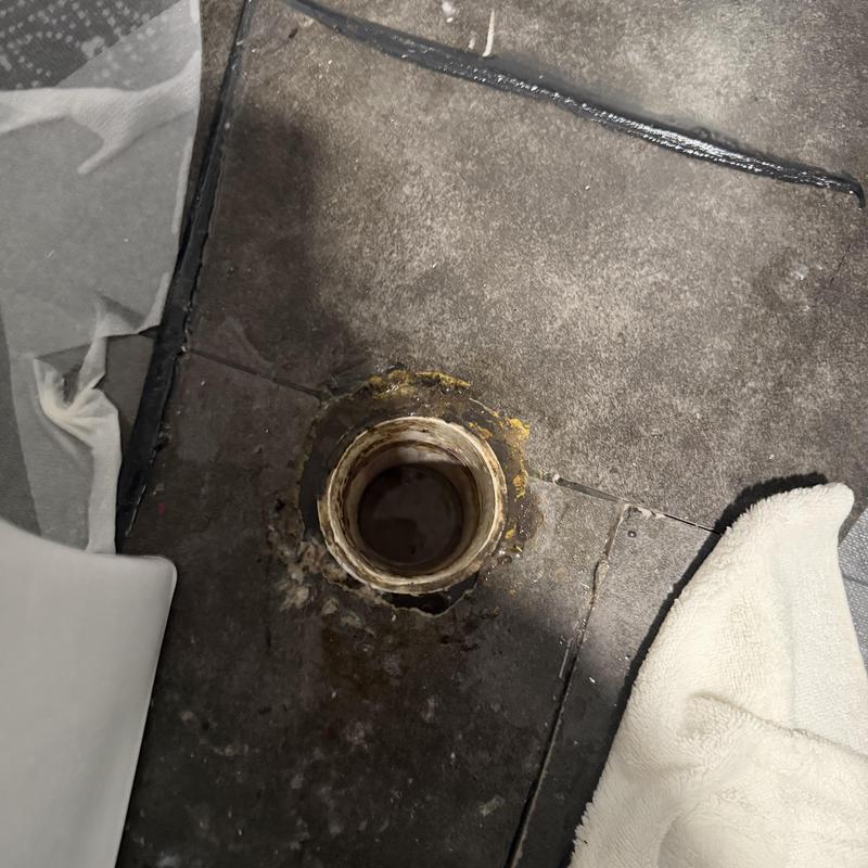 Sewage floor drain opening with surrounding stains and debris