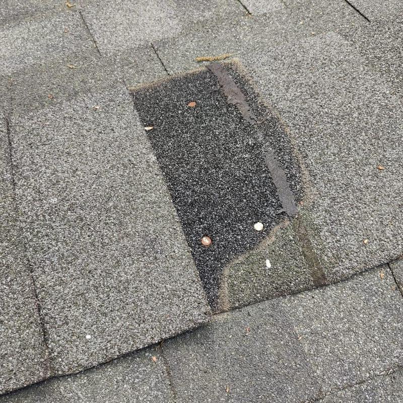 Damaged roof shingle with exposed underlayer and nails