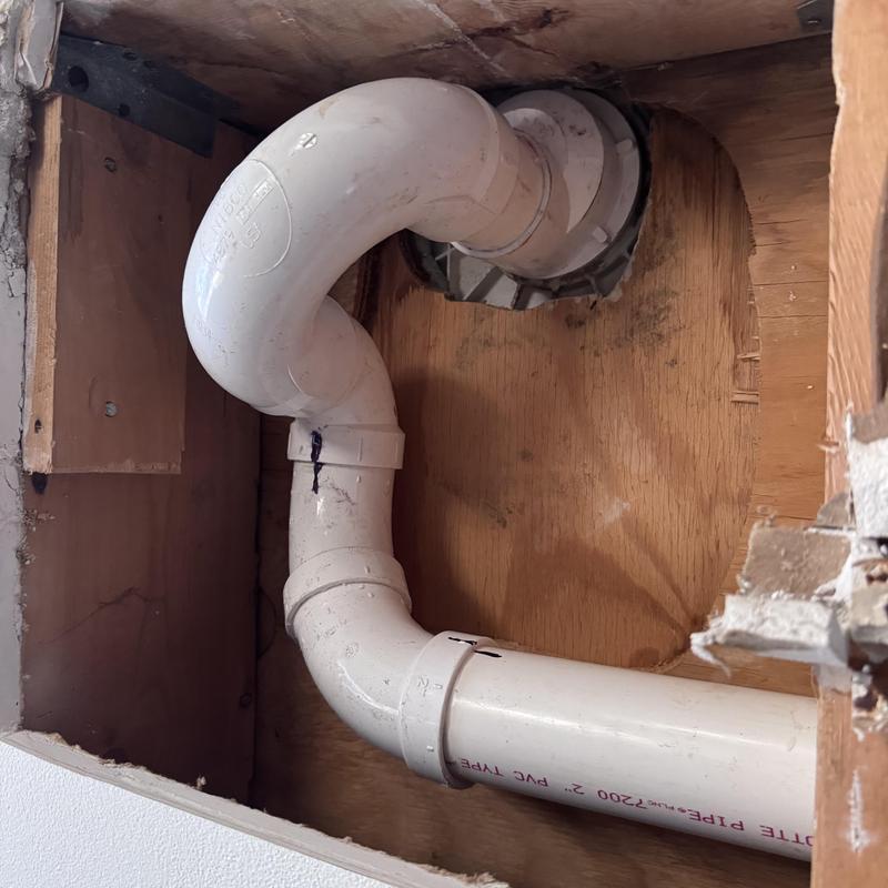 PVC shower drain pipe installation behind wall panel