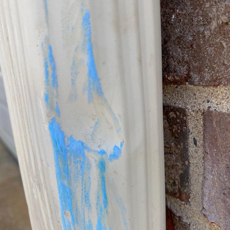 Vinyl door frame with blue paint smudge near brick wall
