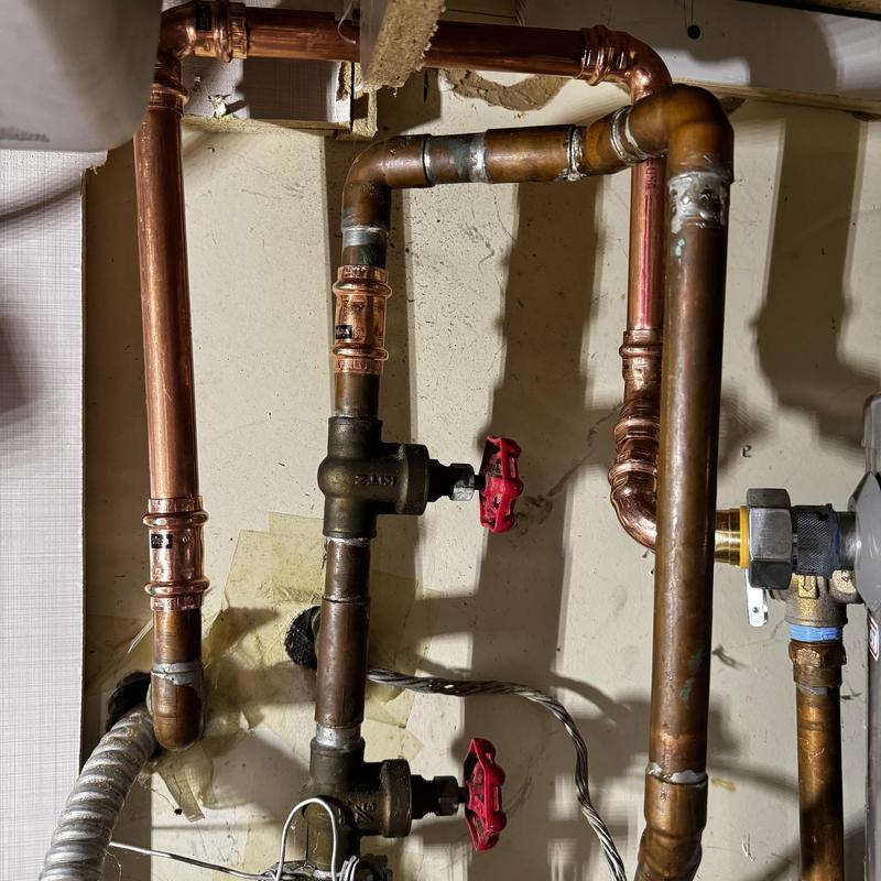 Copper plumbing pipes with red valve handles installed
