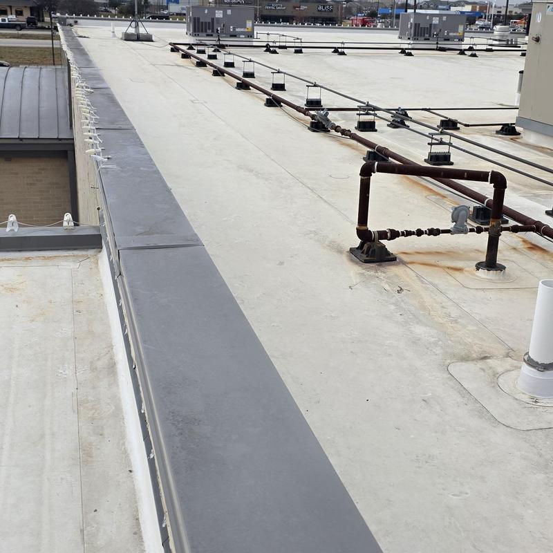 Flat commercial roof with metal piping and HVAC units