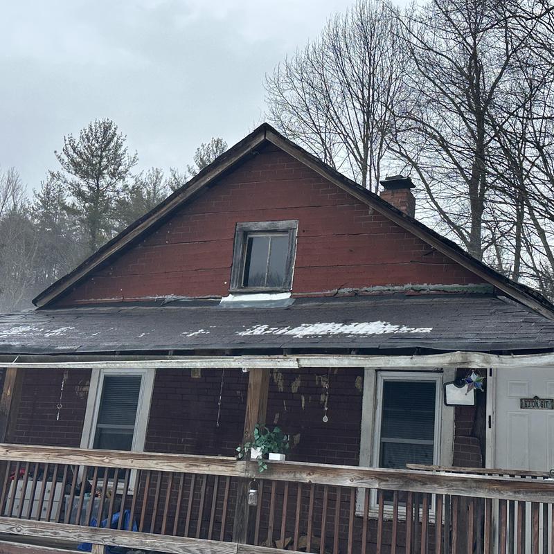 Asphalt shingle roof with snow patches and wear