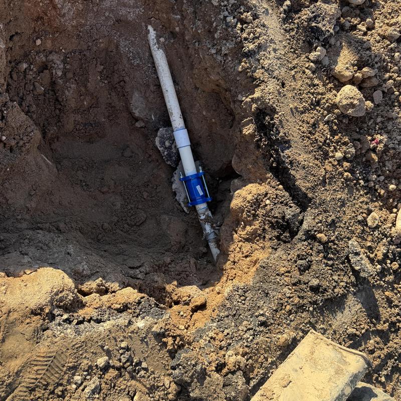 Water main pipe with blue repair coupling in dirt