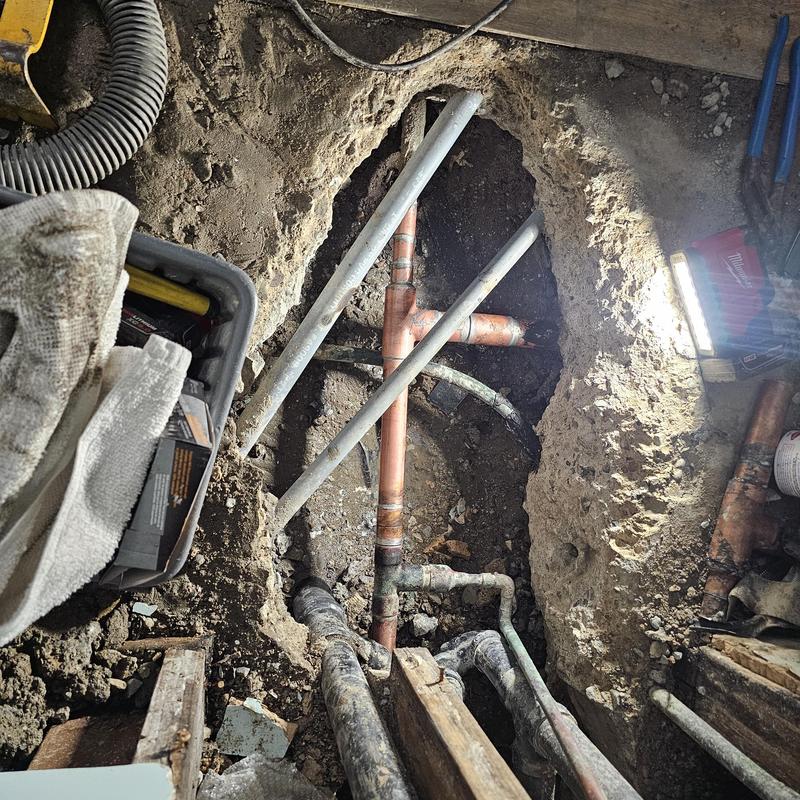 Copper slab water leak pipes exposed in dirt hole