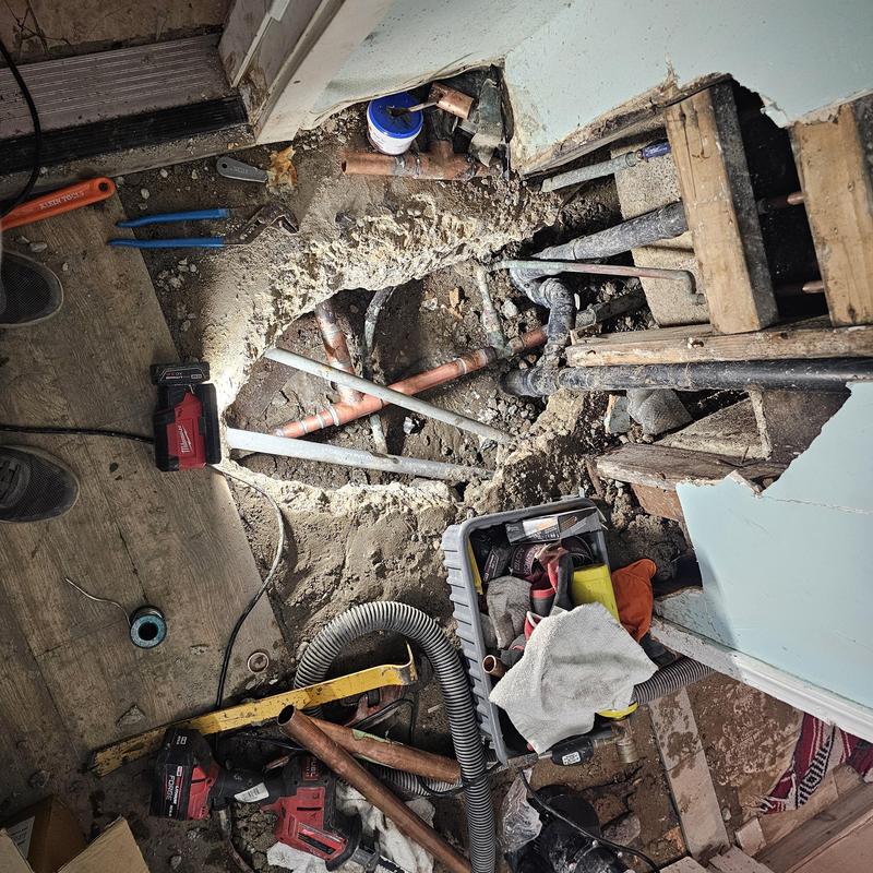 Slab water leak with copper pipes and tools visible