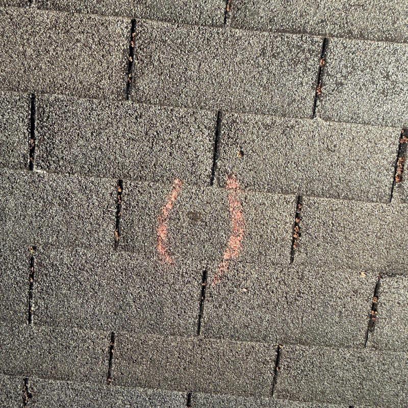 Asphalt shingles with hail damage marked on roof