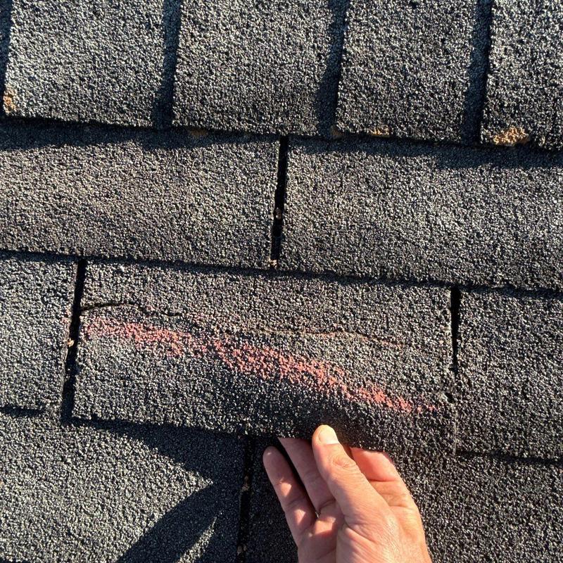 Asphalt shingle with hail damage marked for repair