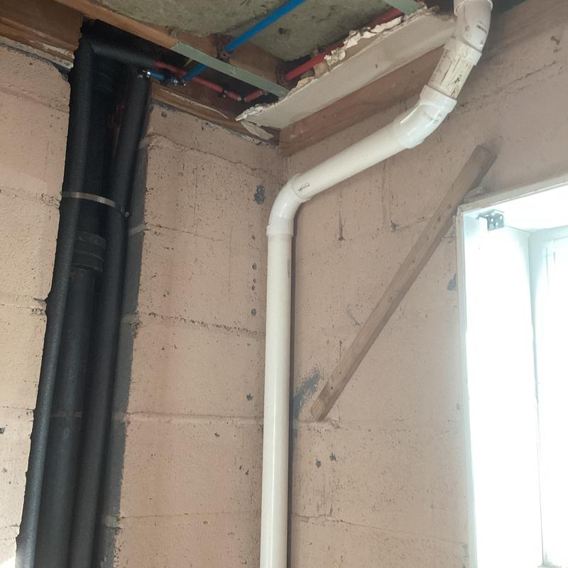 PVC drain pipe installation in basement wall corner