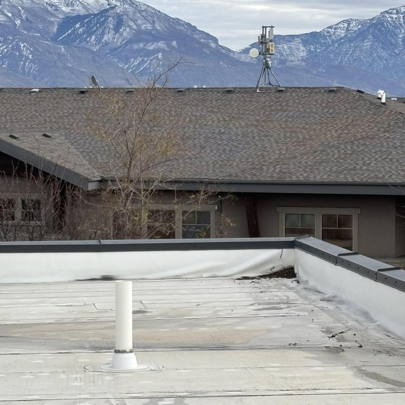 TPO flat roof with vent pipe near residential building
