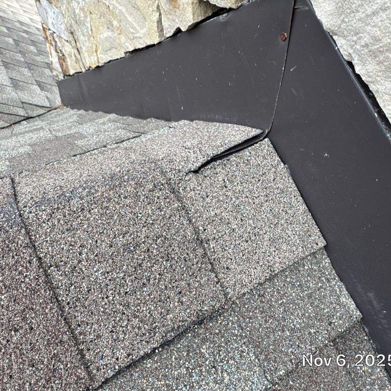 Roof flashing and asphalt shingles near stone wall