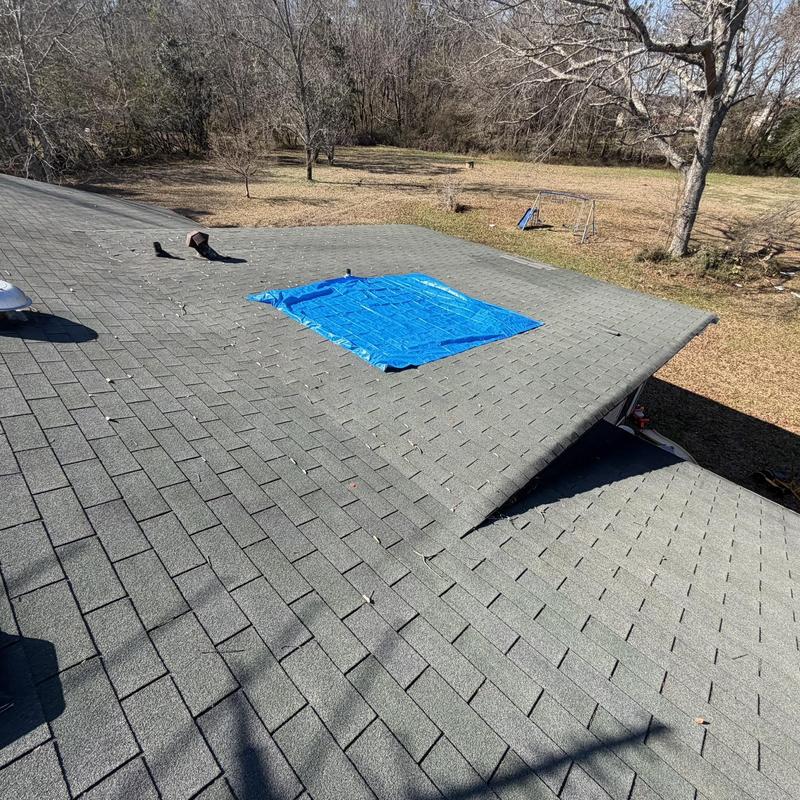 Roof decking with blue tarp covering damaged area
