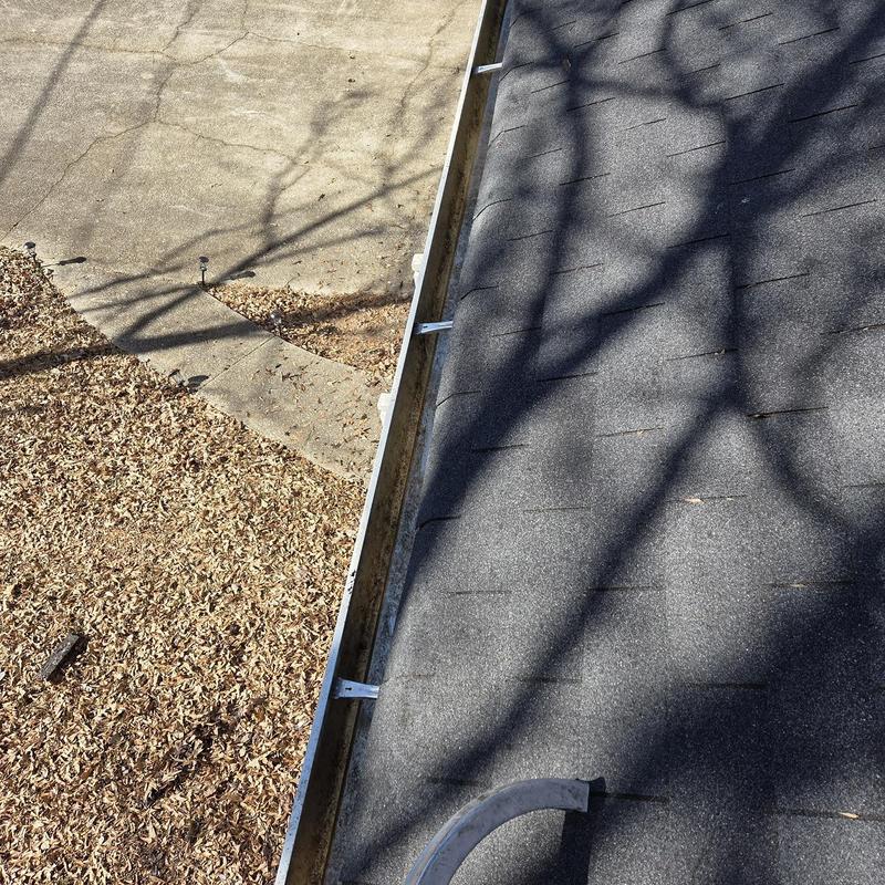 Gutter cleaning along asphalt shingle roof edge