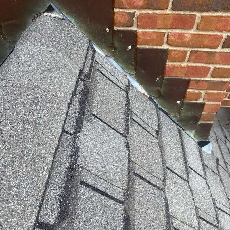 Asphalt shingles near brick chimney flashing inspection