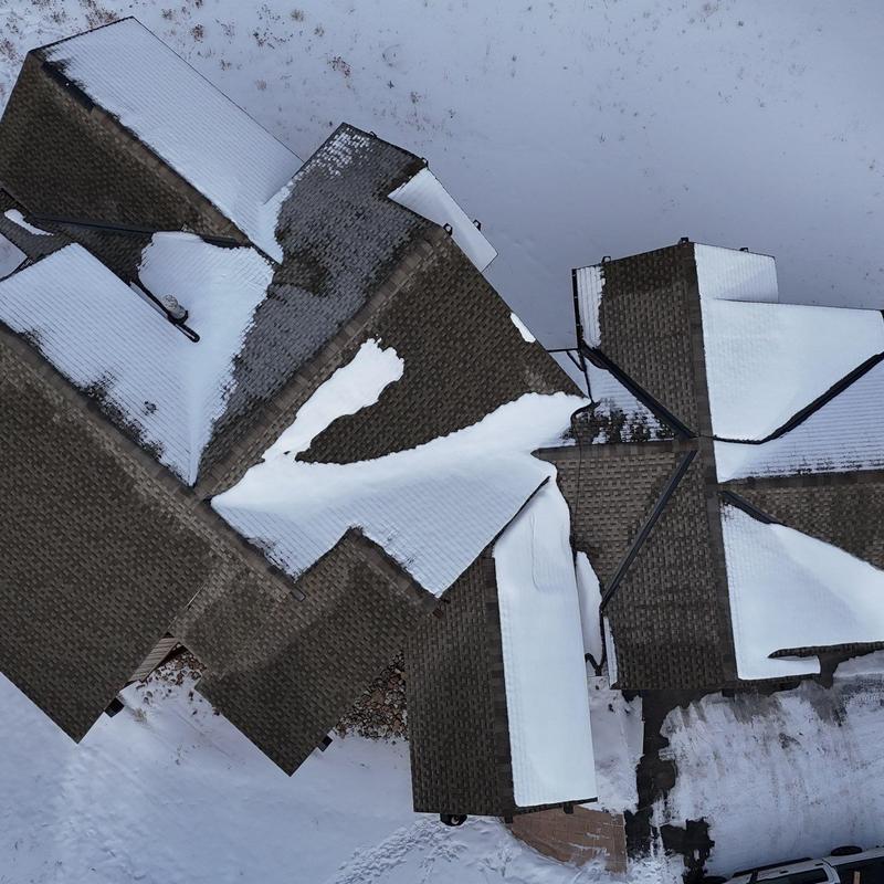 Asphalt shingle roof with snow patches overhead view