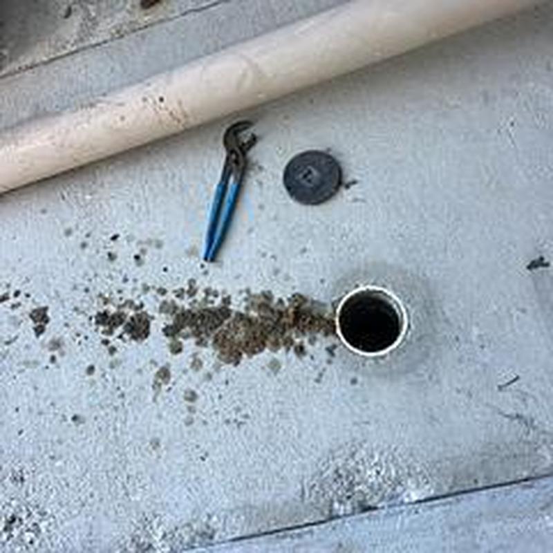 Drain cleanout pipe with plumbing tools and debris on pavement