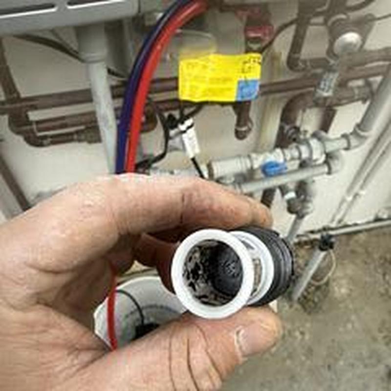 Water heater condensate cap held by technician hand