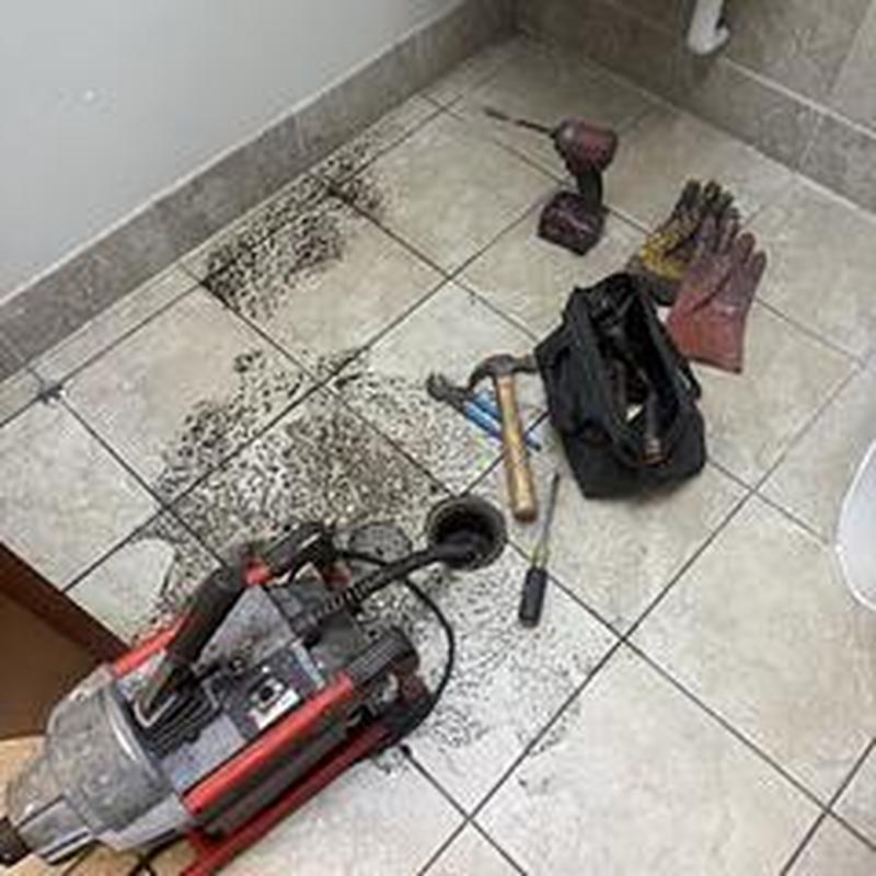 Floor drain clog clearing with power auger in restroom