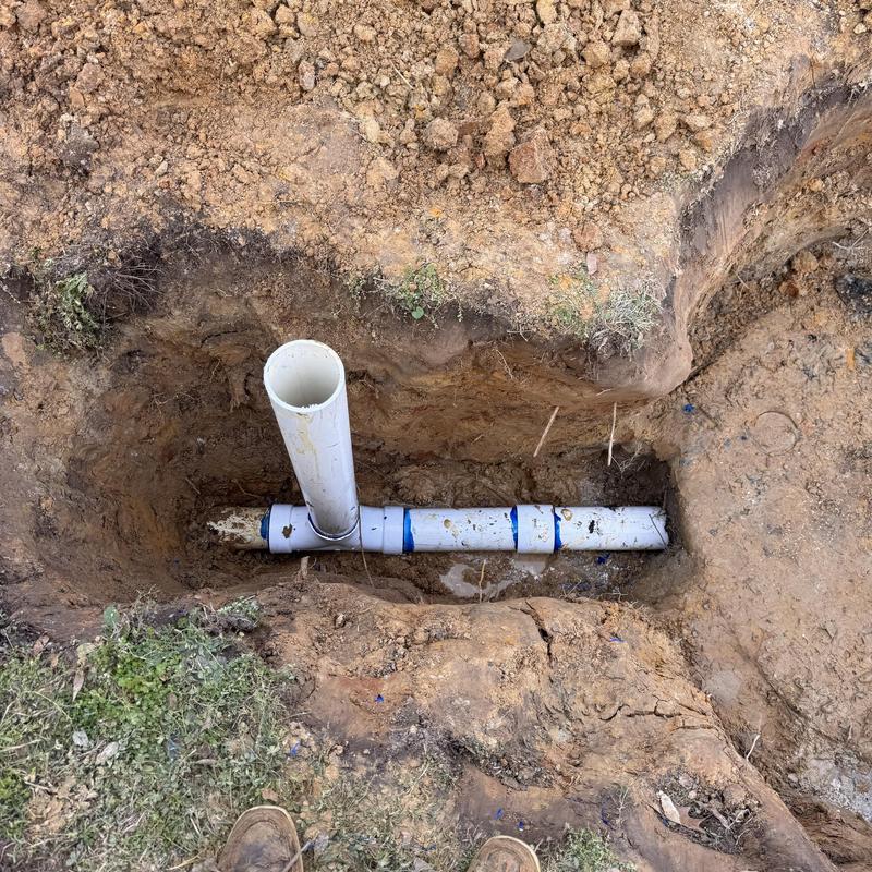 Sewer line with vertical cleanout pipe in trench