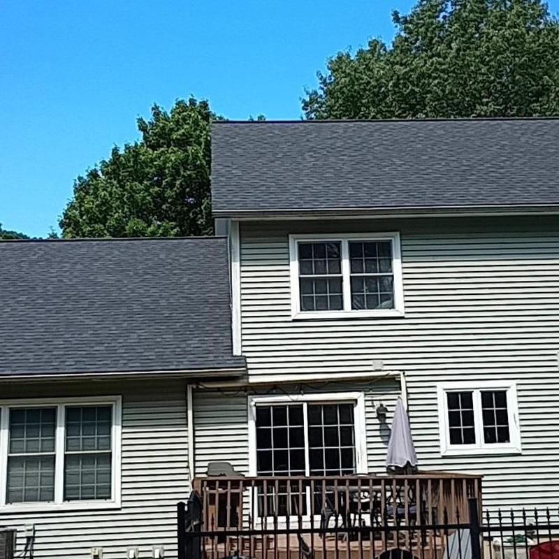Asphalt shingle roof on two-story home in bright daylight
