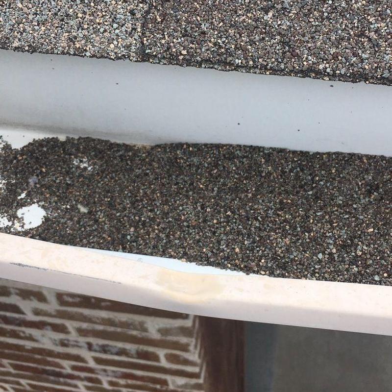 Gutter filled with roof shingle granules after hailstorm