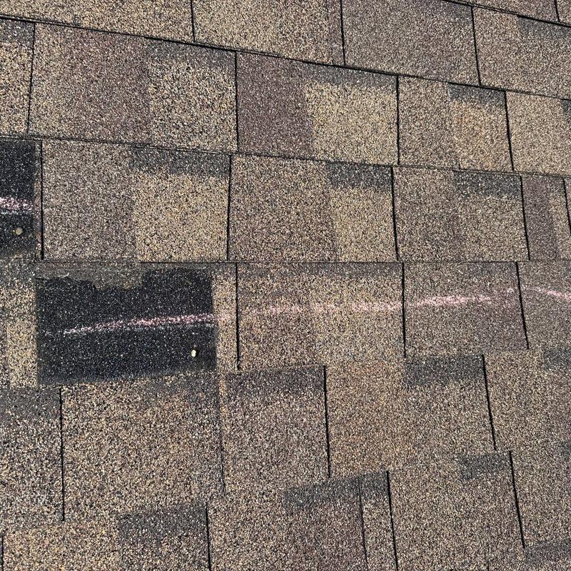 Asphalt shingles with hail damage marked for repair