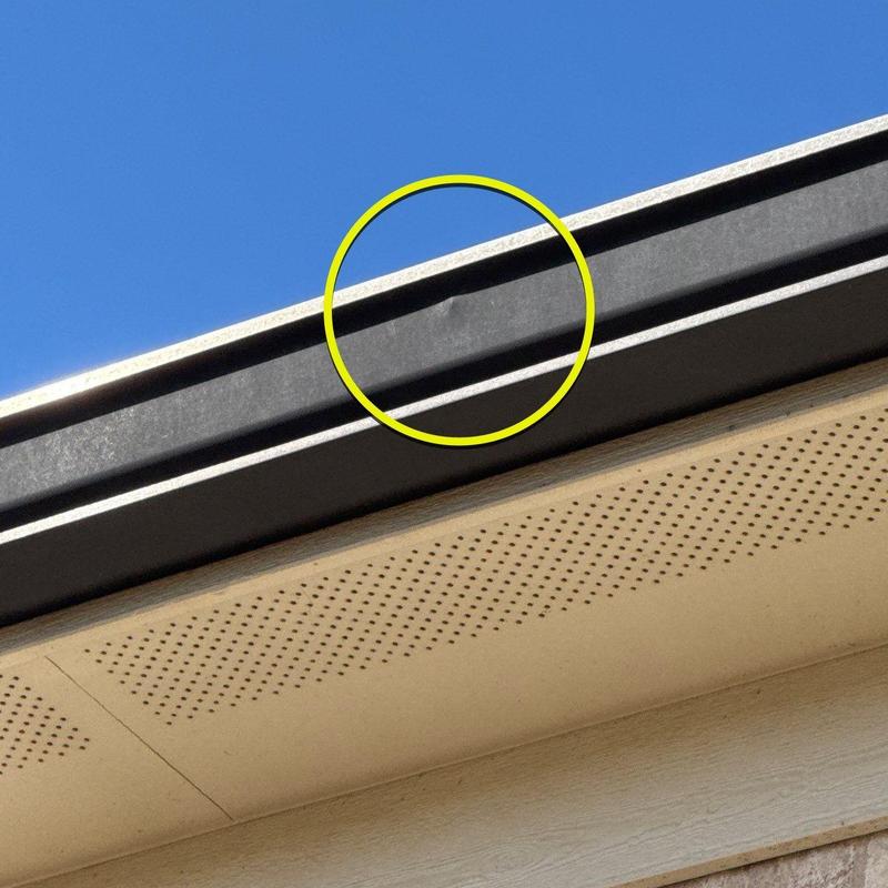 Metal gutter dent with circled damage on home exterior
