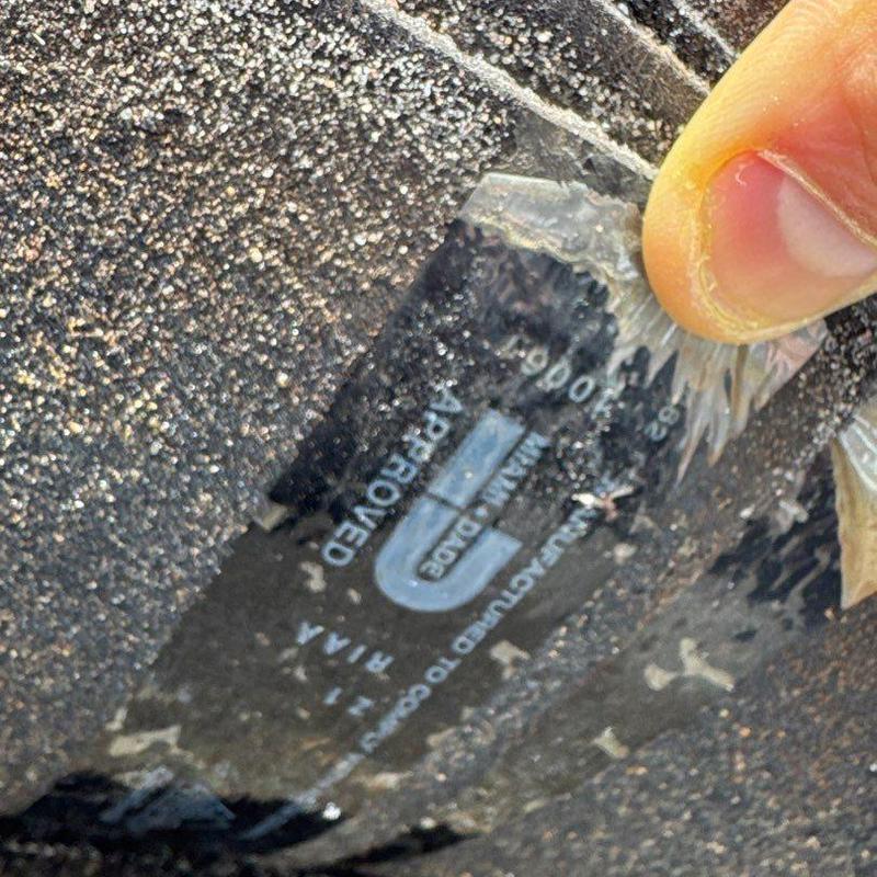 Asphalt shingle roof with manufacturer label being peeled back