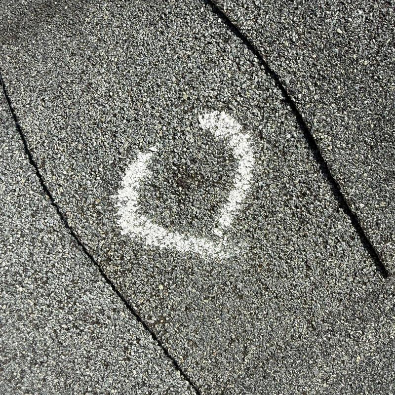 Asphalt shingles with hail damage marked on roof