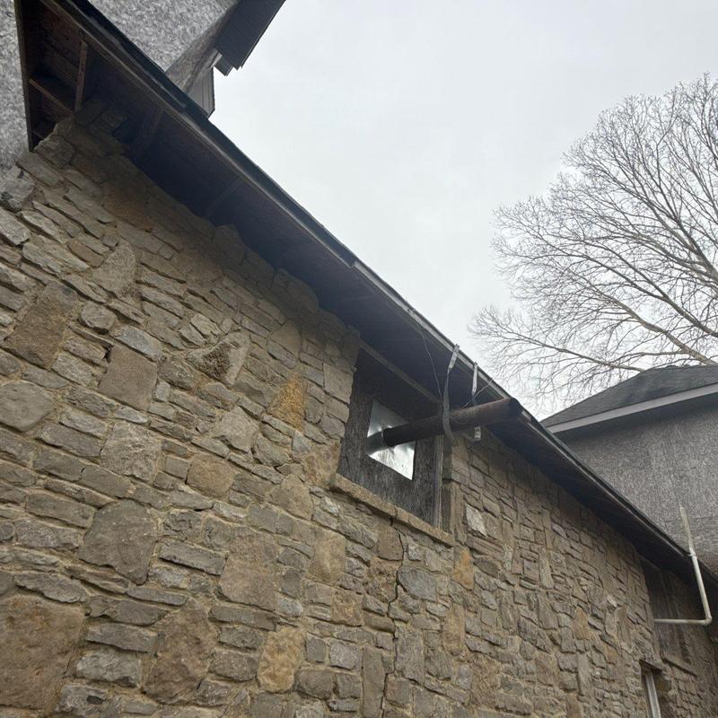 Roof flashing damaged on stone schoolhouse exterior
