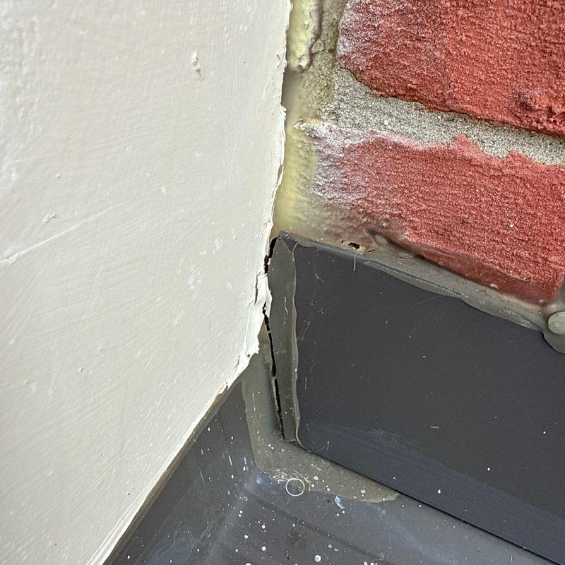 Flashing seal gap on metal roof edge near brick wall