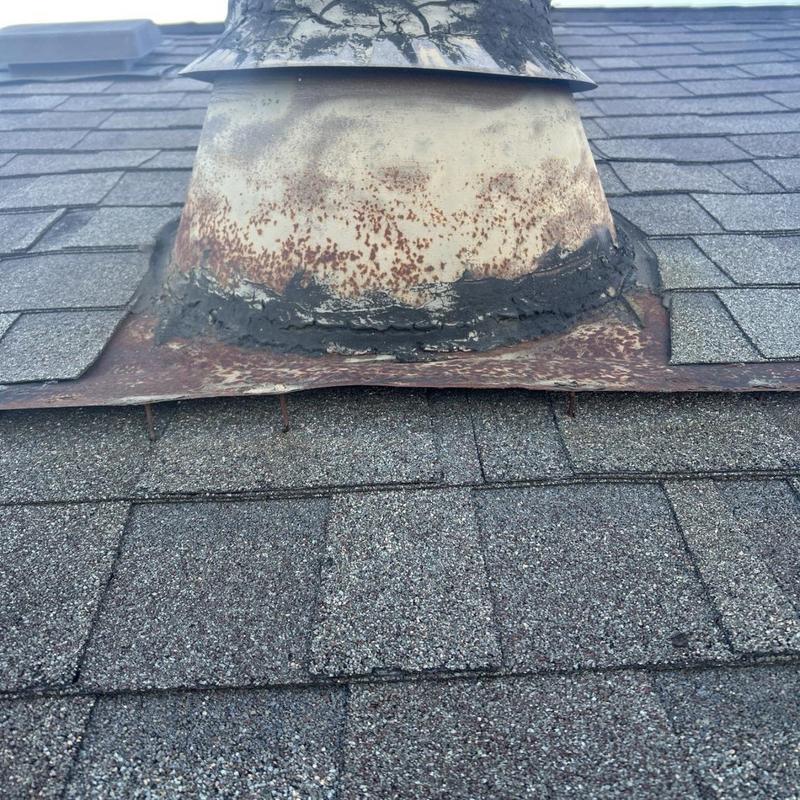 Rusted metal roof vent flashing with sealant damage