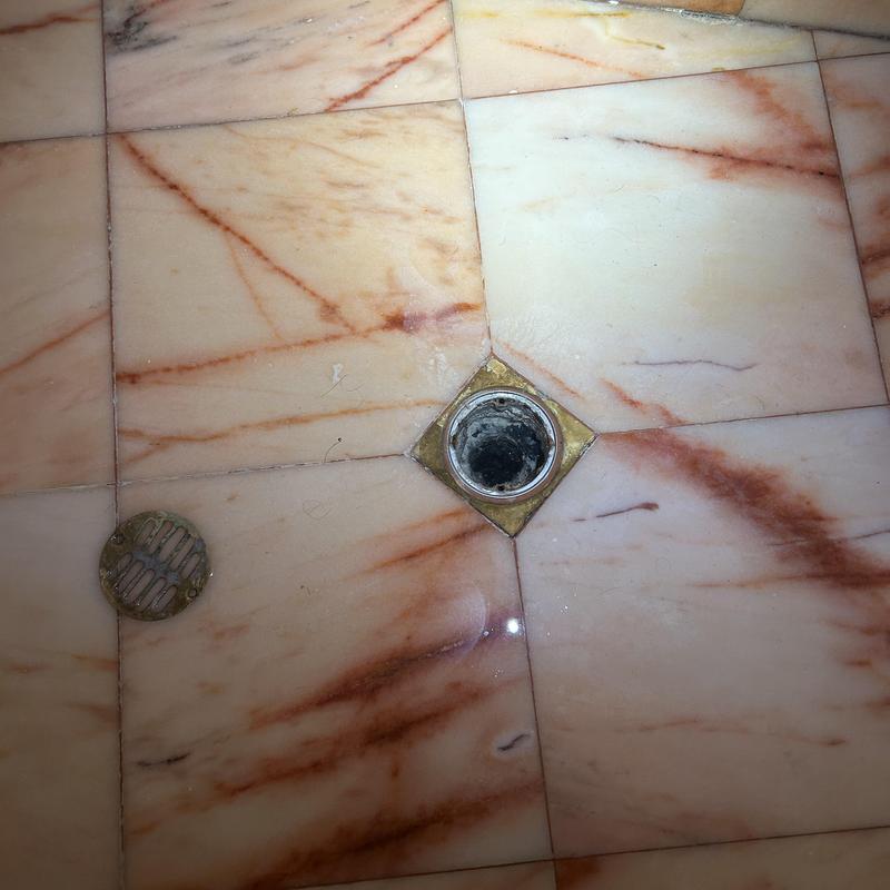 Shower drain pipe with removed cover on tile floor